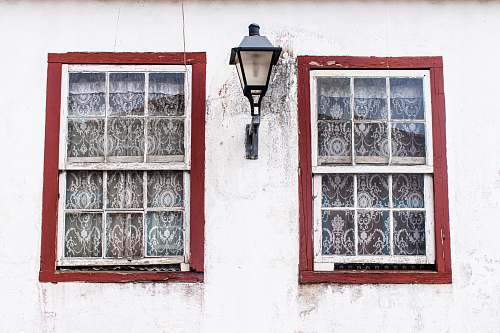 home decor turned-off sconce lamp between two windows curtain